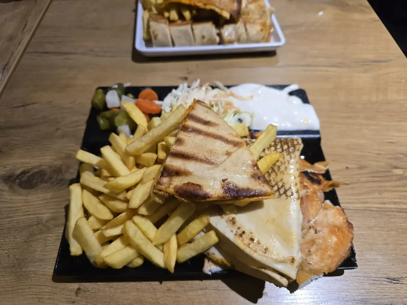 Gegrilltes Sandwich mit Pommes und Beilagen auf Schieferplatte